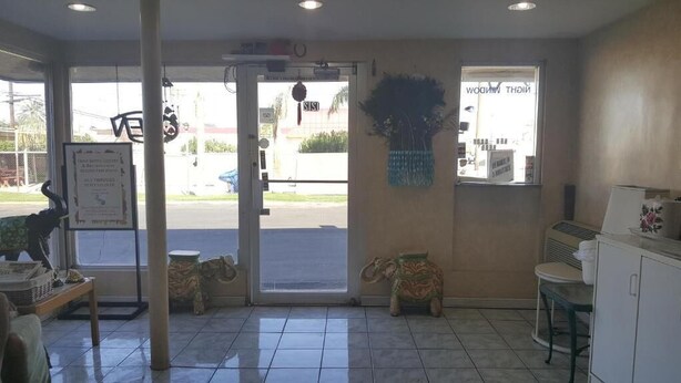 A reception area with a tiled floor, a reception desk, a decorative elephant sculpture, and a window with a view of the street. - Budget Inn and Suites El Centro (El Centro)