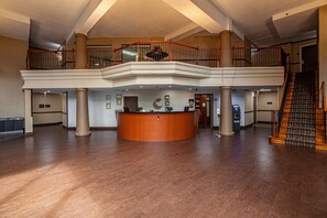 Un vestíbulo amplio con una mesa de recepción, una escalera y un entrepiso.