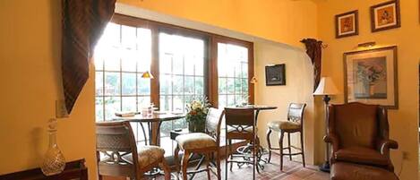 A dining area with a table and chairs, a window with curtains, and a chair.