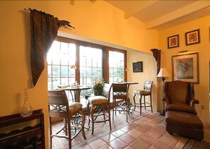 A dining area with a table and chairs, a window with curtains, and a chair.