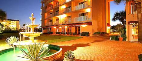 A hotel with a courtyard, a fountain, and a pool.