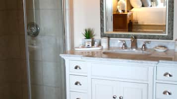 A bathroom with a glass shower enclosure, a white vanity with a sink, and a large mirror above the vanity.