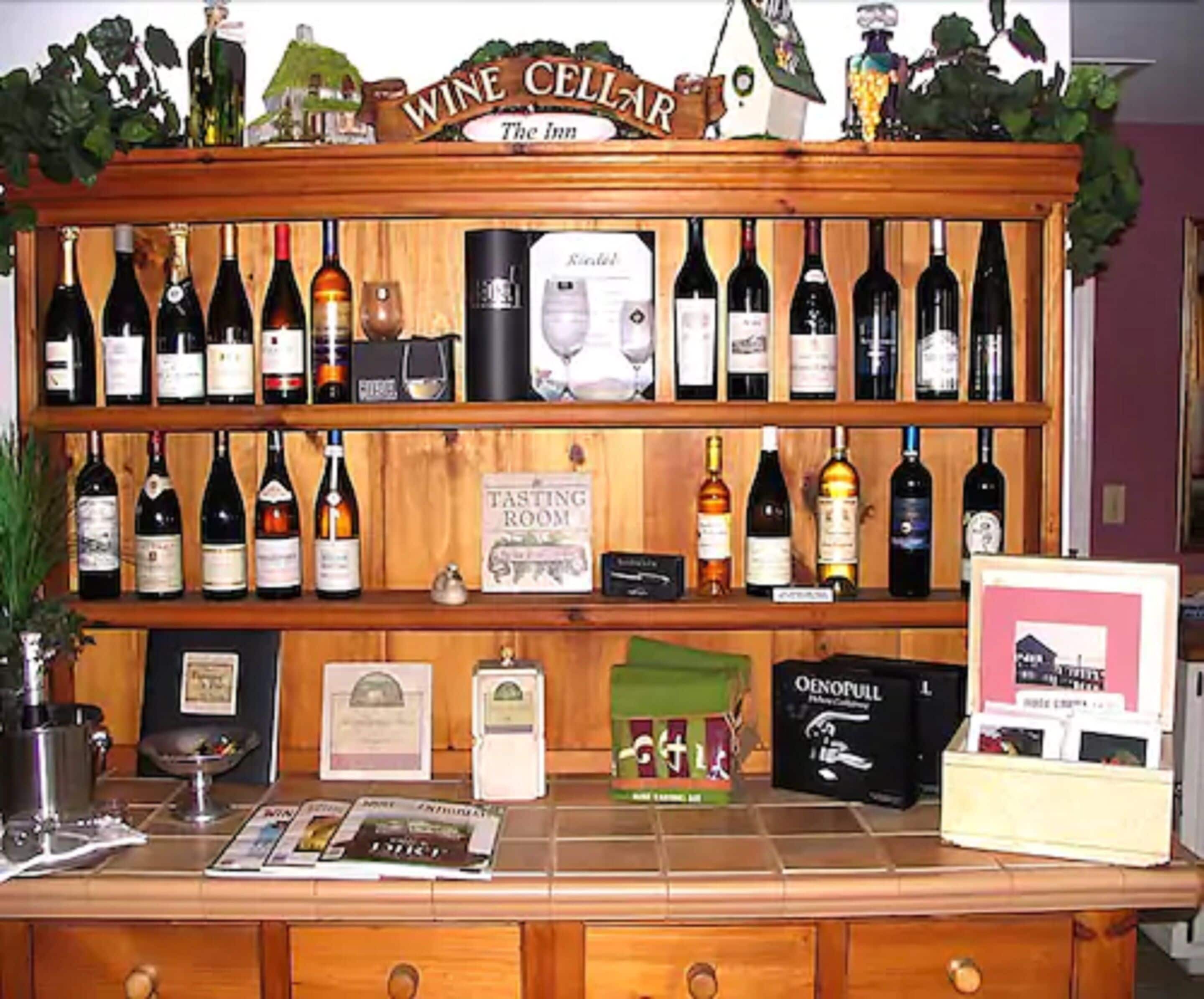 Une cave à vin avec des étagères remplies de bouteilles, une enseigne indiquant une salle de dégustation, et divers objets liés au vin exposés sur le comptoir.