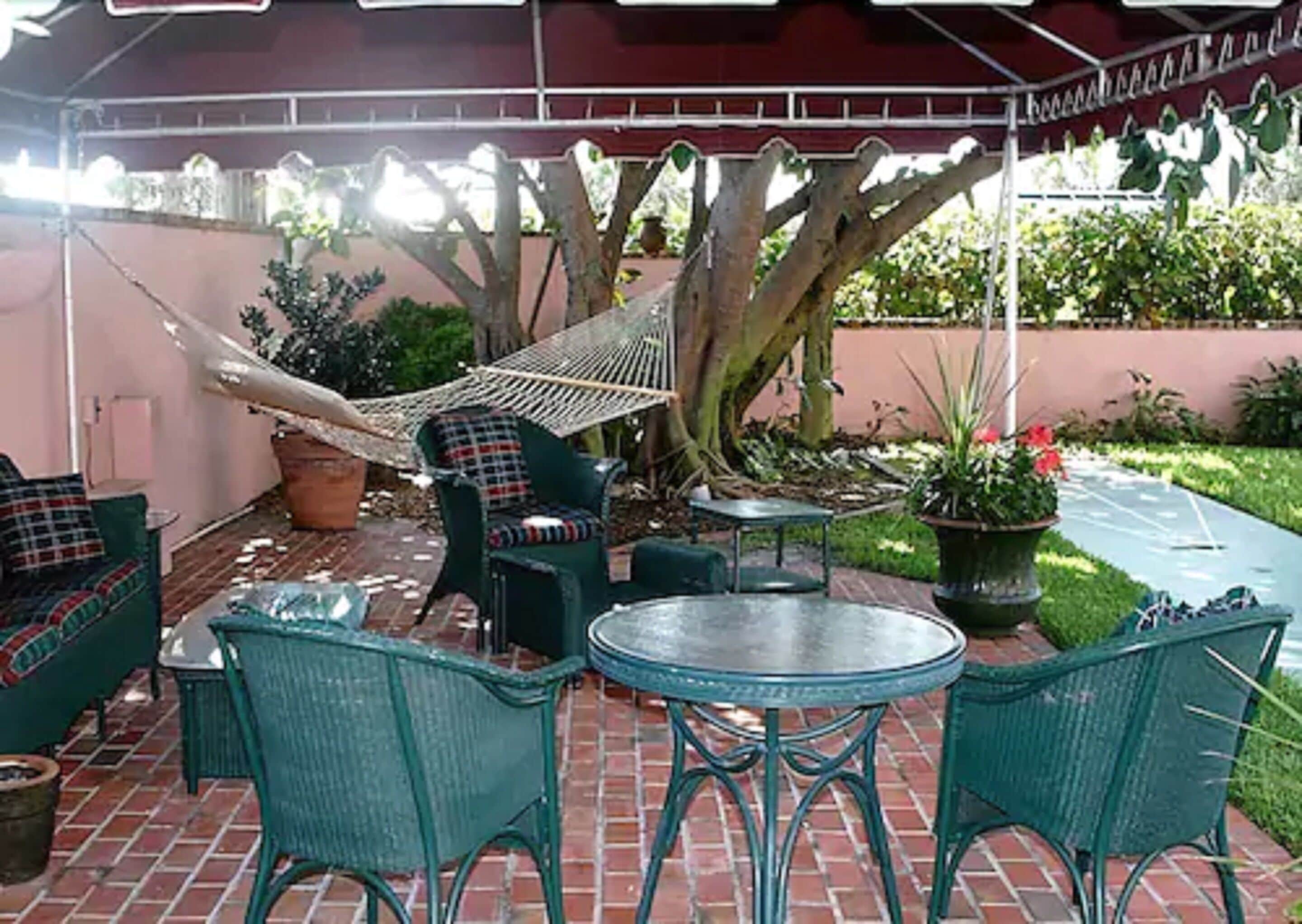 A patio area with green wicker furniture, a hammock, and a potted plant.