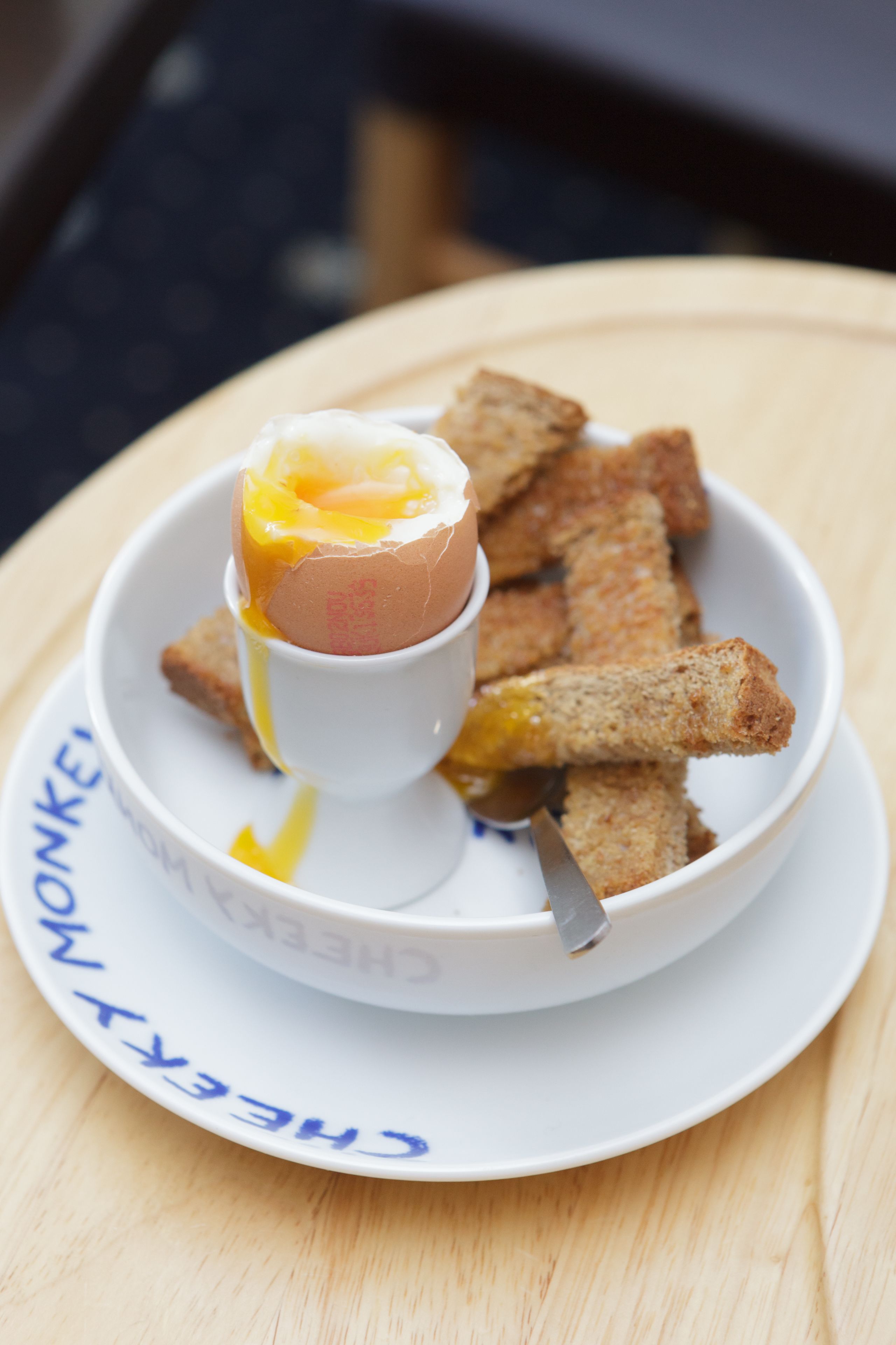 A breakfast plate with a poached egg, toast, and a spoon.