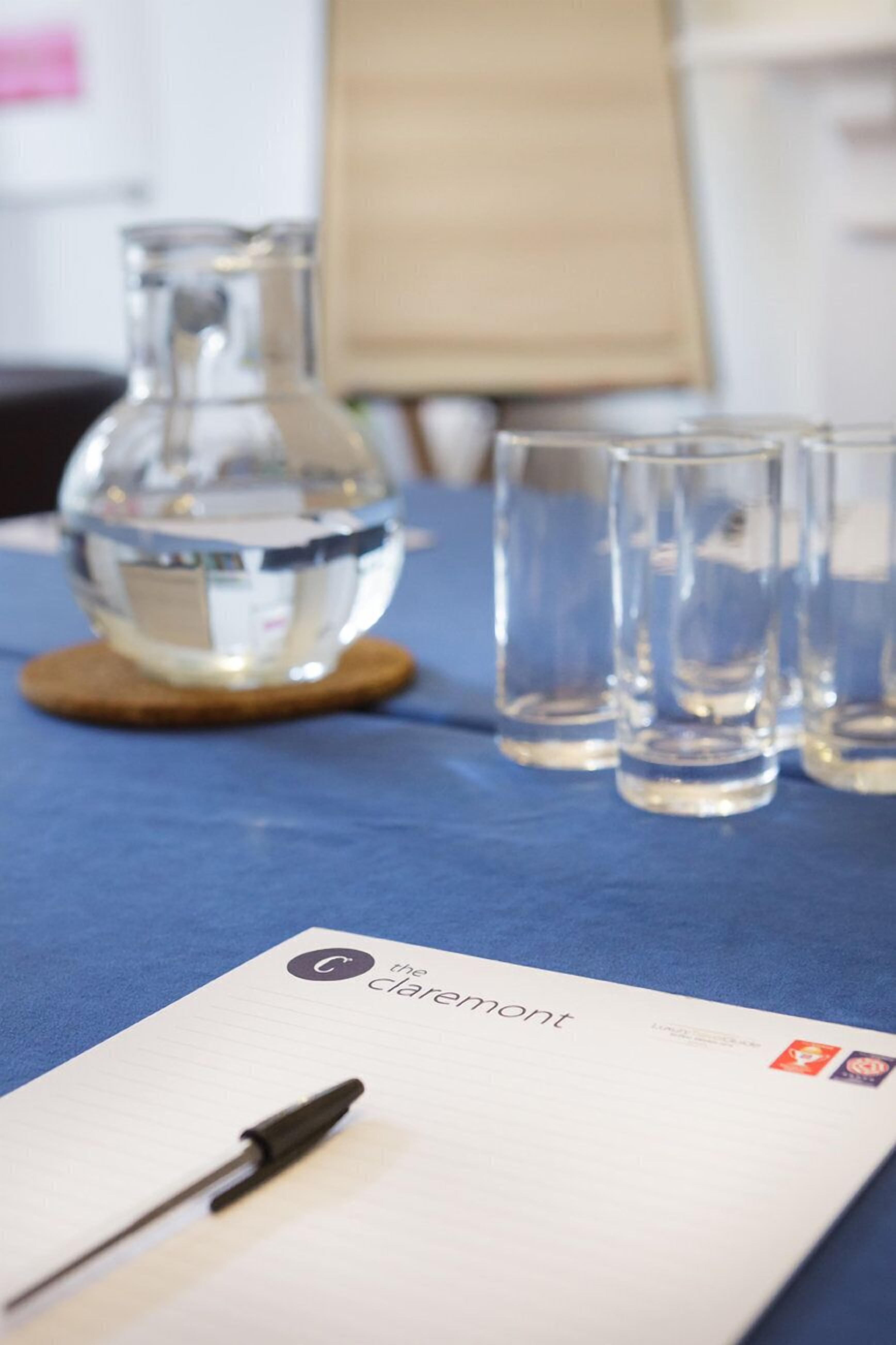 A table with a notebook, a pen, and a glass pitcher.