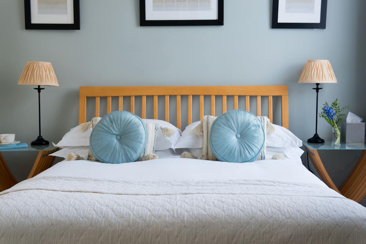 A neatly made bed with a wooden headboard, two bedside lamps, and a framed picture on the wall.