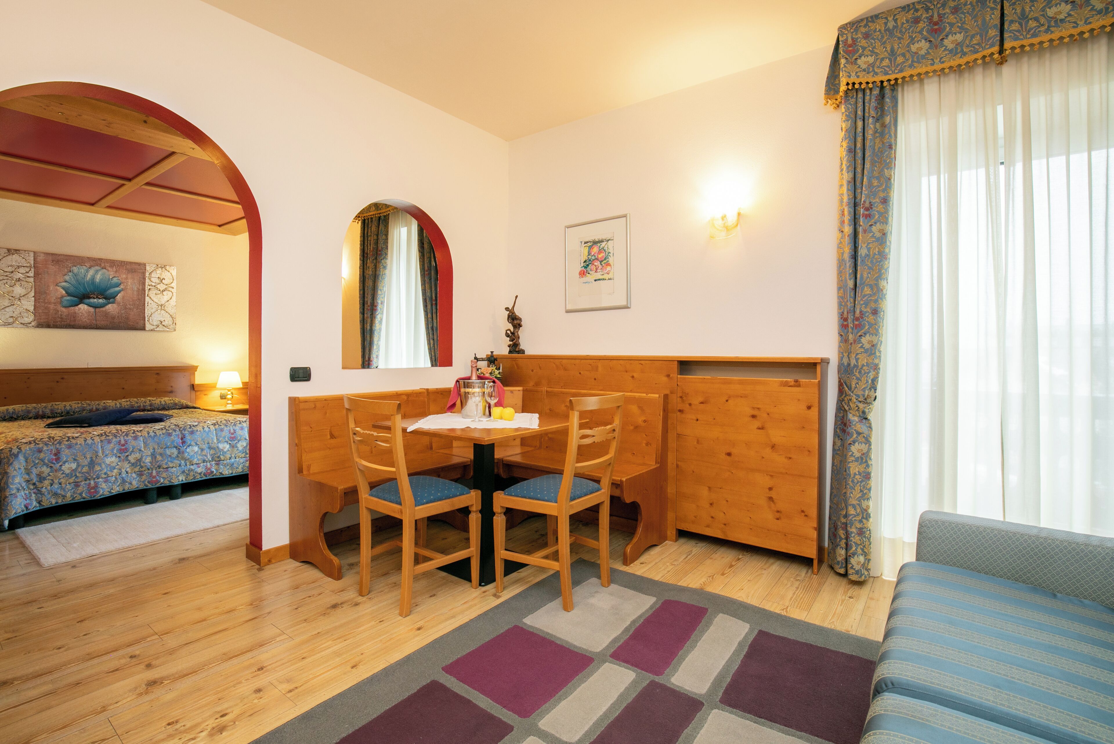 A cozy room with a wooden dining table, two chairs, a bench, and a sofa.