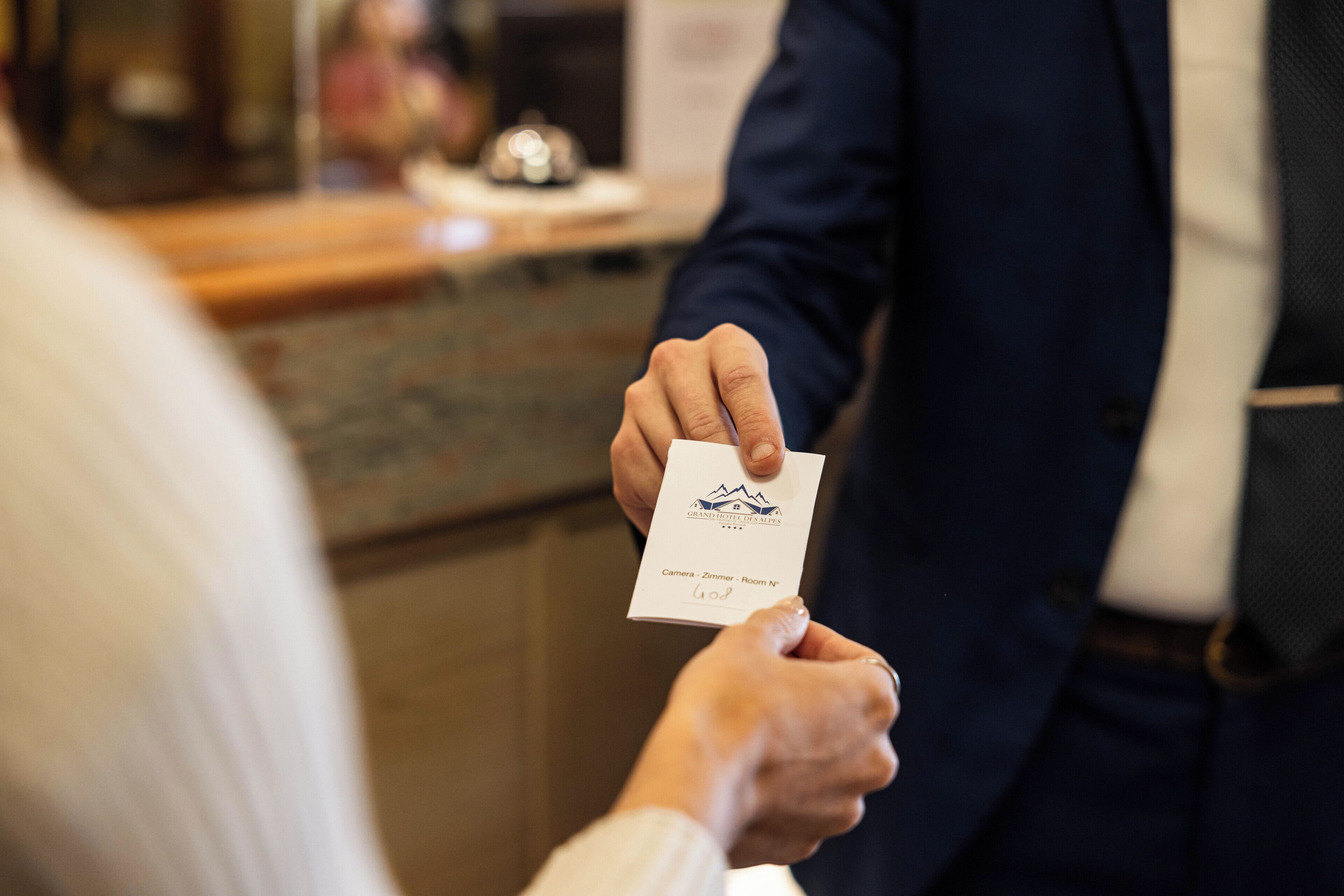 A person handing over a business card to another individual in a formal setting.