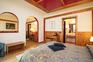 A bedroom with a bed, a desk, a chair, and a small bench. - Grand Hotel des Alpes (Primiero San Martino di Castrozza)