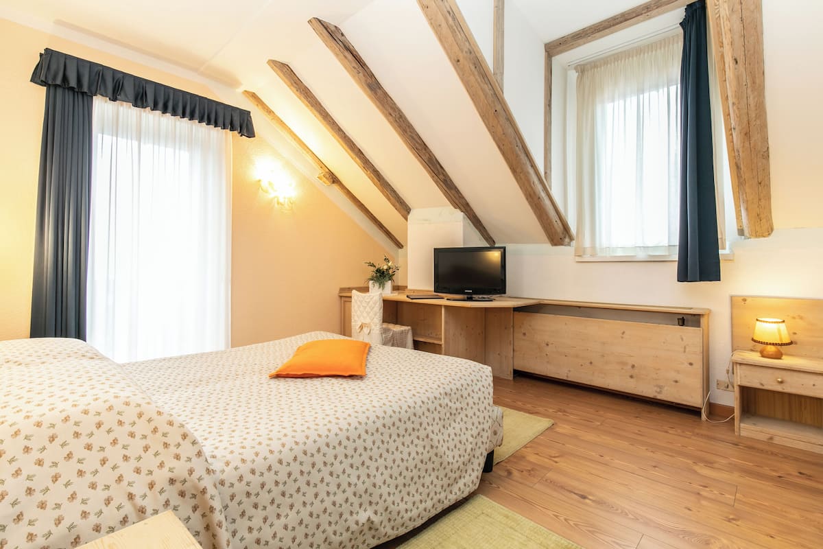 Ein Schlafzimmer mit einem Bett, einem Schreibtisch, einem Fernseher und einer Lampe.