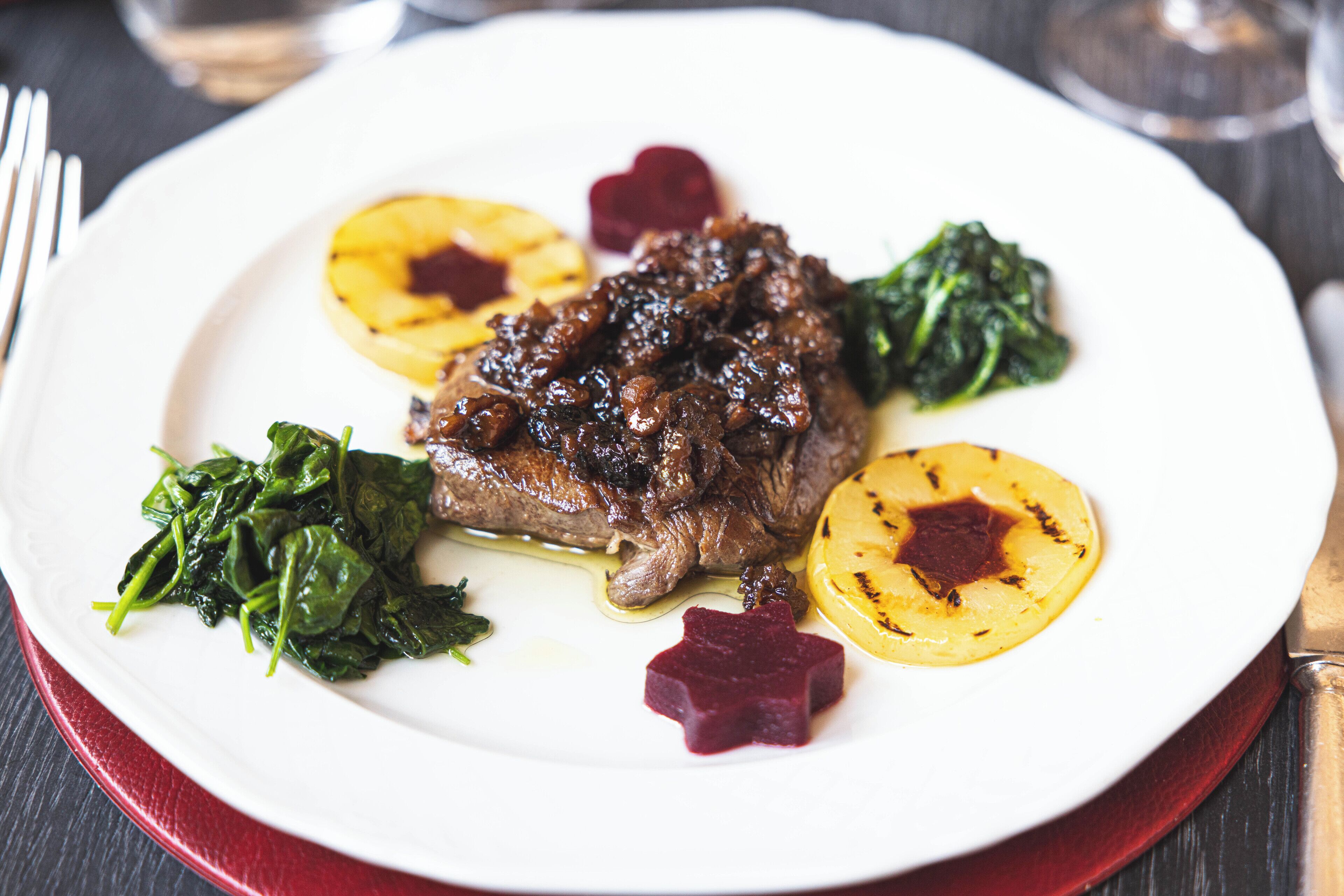 Une assiette de nourriture comprenant un morceau de viande, des pommes de terre rôties et des légumes verts.