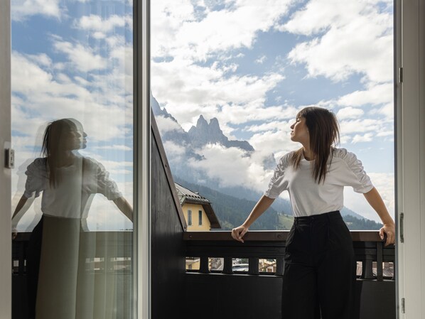 A room with a large window overlooking a mountainous landscape. - Grand Hotel des Alpes (Primiero San Martino di Castrozza)