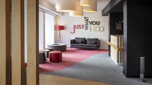 A modern interior with a grey sofa, red ottoman, and a red floor lamp. - Stay Hotel Faro Centro (Faro)