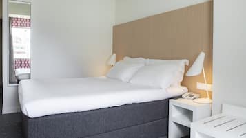 Una habitación de hotel moderna con una cama grande, lámparas de noche, una mesita de noche y un espejo.