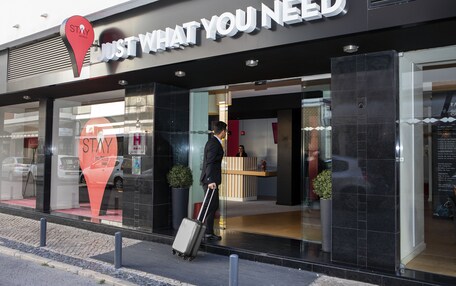 A hotel entrance with a reception desk and a sign that reads "STAY WHAT YOU NEED".