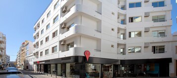 Un hotel de varios pisos con balcones, ventanas amplias y un llamativo letrero que dice 'Stay'.