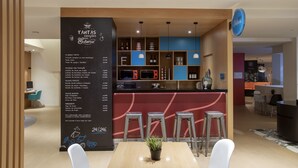 A modern restaurant with a black menu board listing food items and prices, a bar area with stools, and a seating area with a table and chairs. - Stay Hotel Faro Centro (Faro)