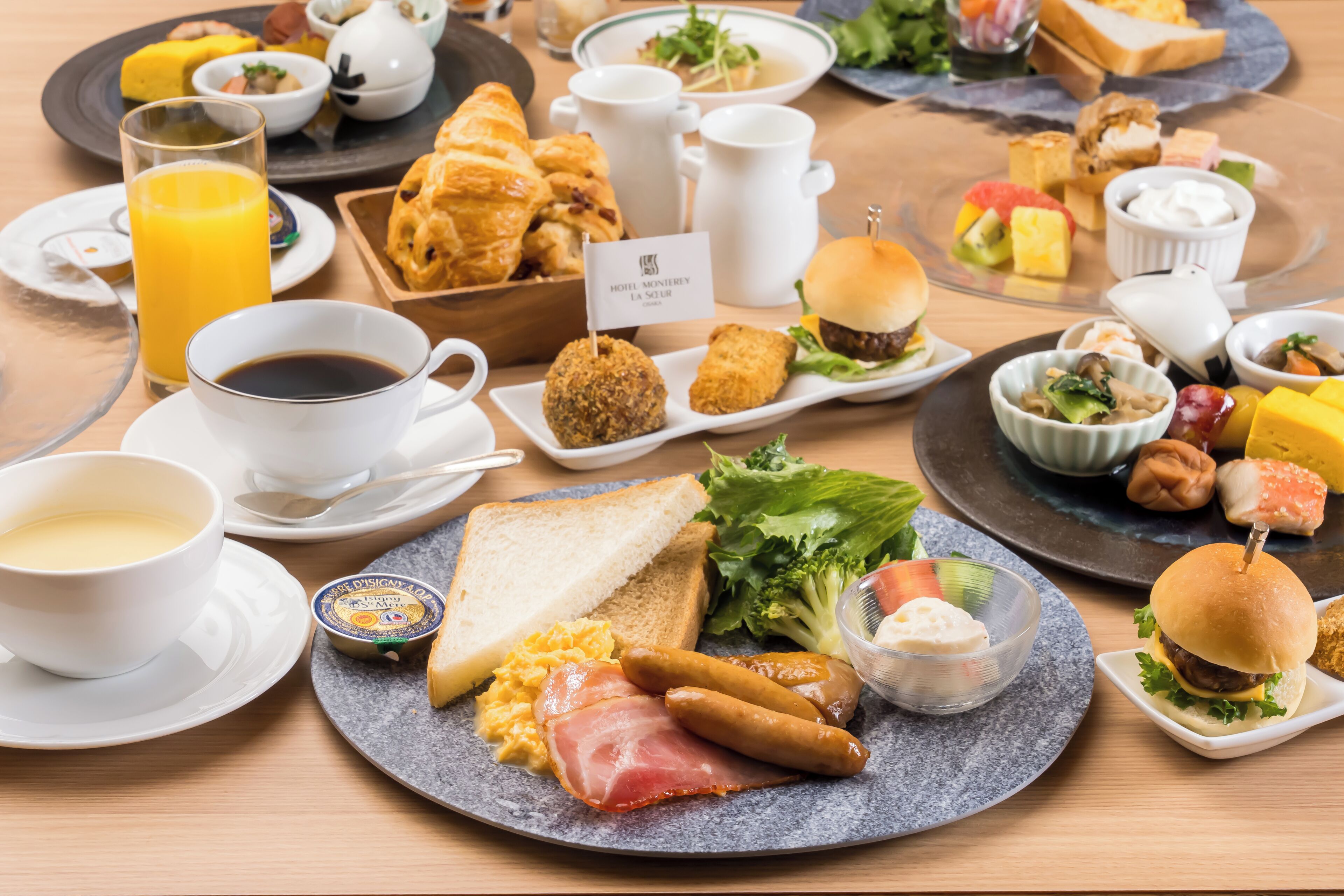 A breakfast buffet with various dishes, including eggs, sausages, and a sandwich.