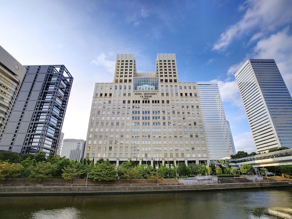 Un hôtel moderne doté d’un atrium central, entouré de gratte-ciel, avec une rivière en premier plan.
