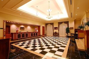 A lobby with a checkered floor, a reception desk, and a chandelier.