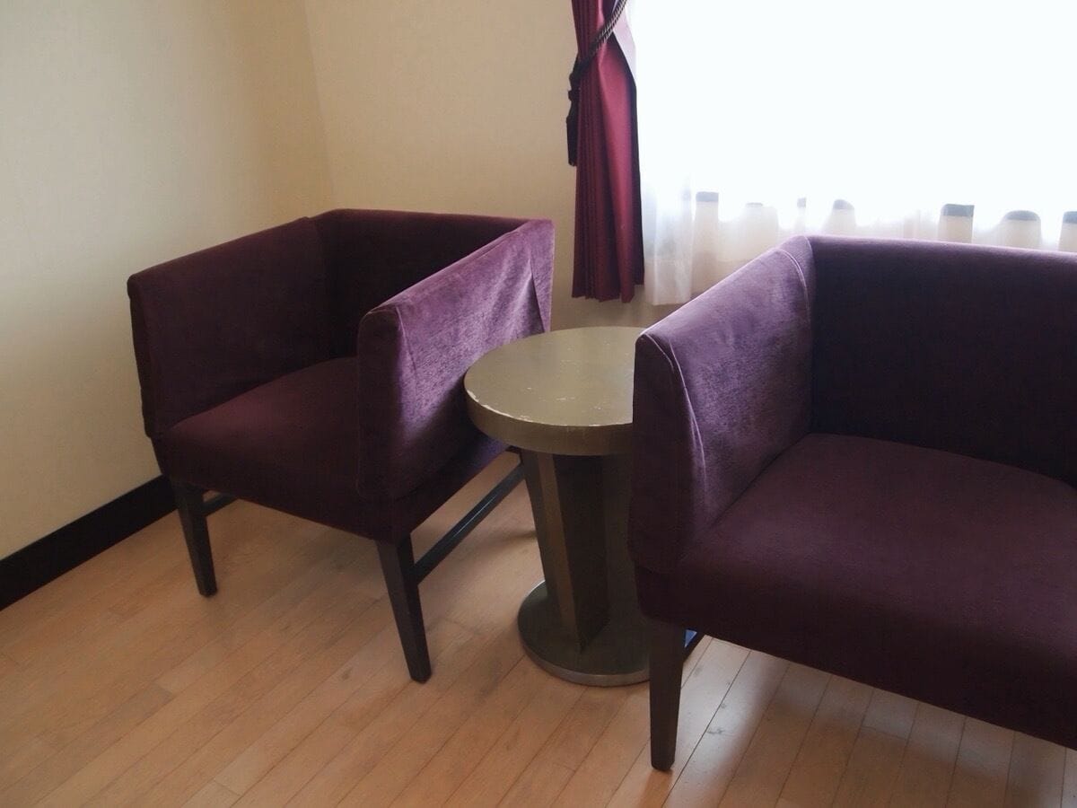 A room with two purple armchairs and a small round table.