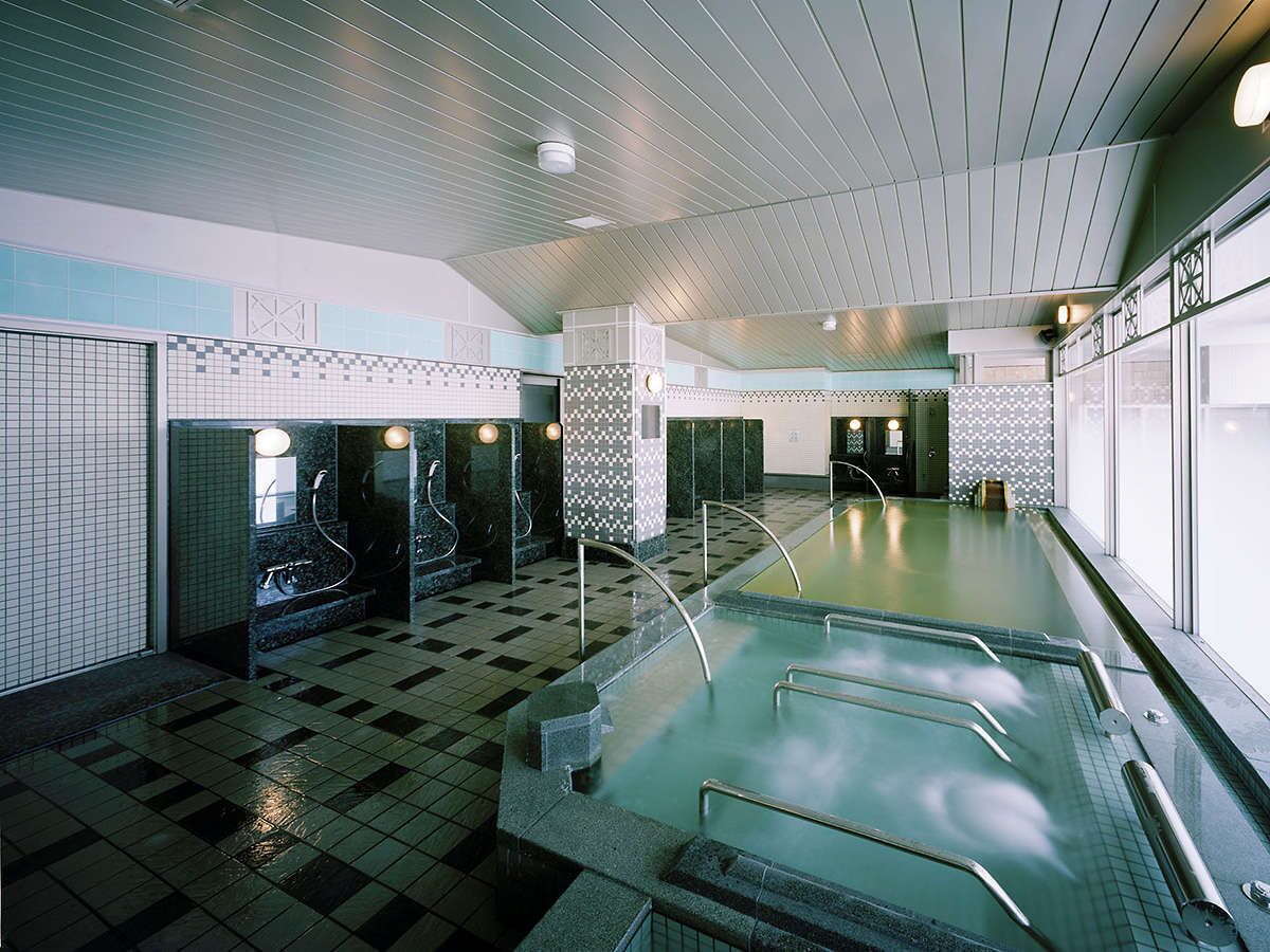 Ein großes Hallenbad mit mehreren Bahnen, gefliesten Wänden und einem Schachbrettboden.