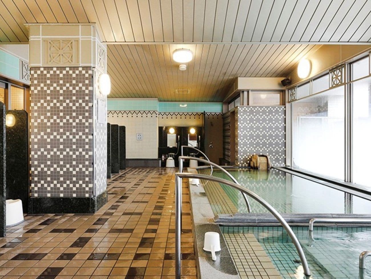 Eine Hottelobby mit Schwimmbecken, Schachbrettfliesen und einer Wand mit geometrischem Muster.