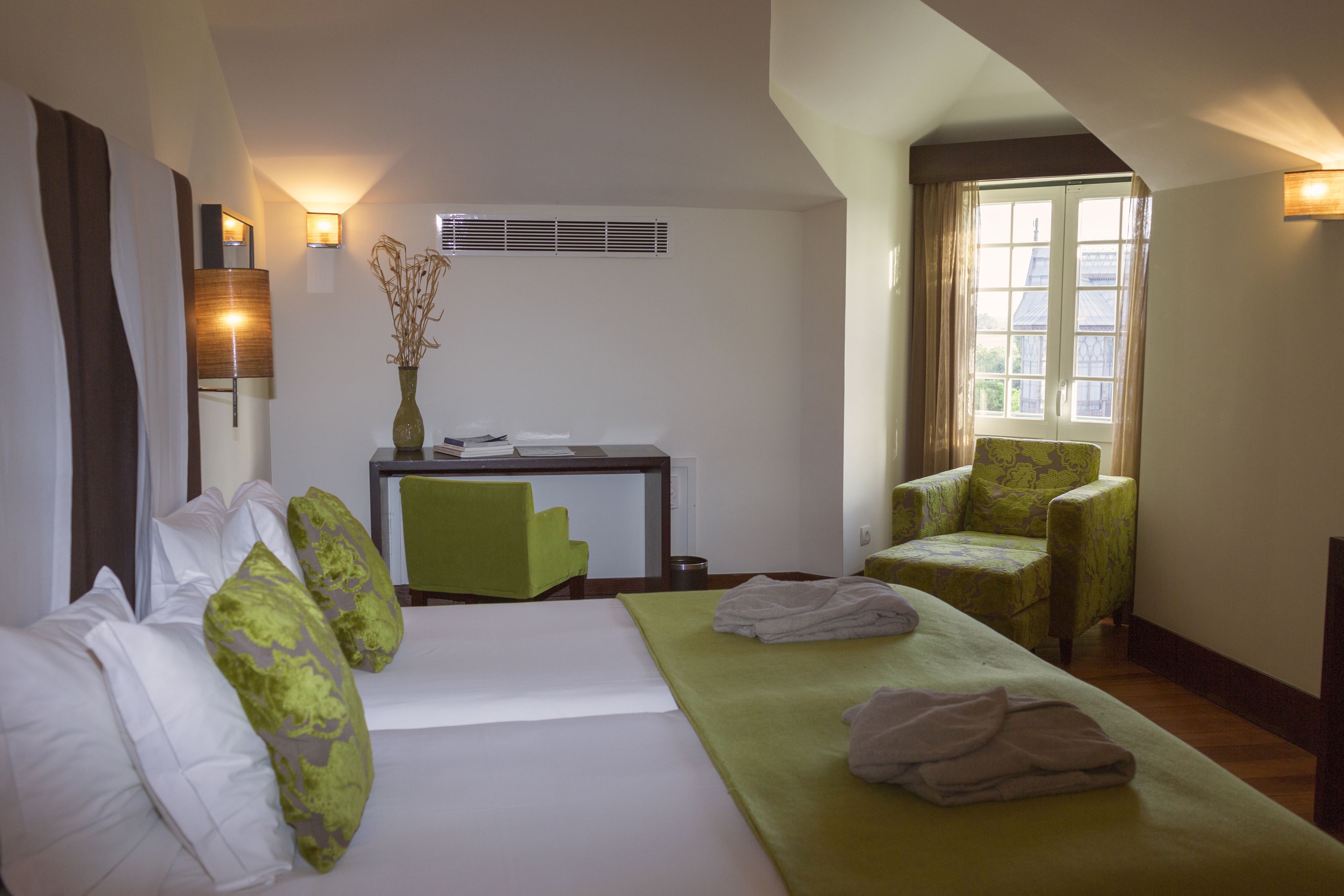 Una habitación de hotel con cama, escritorio, silla y ventana.
