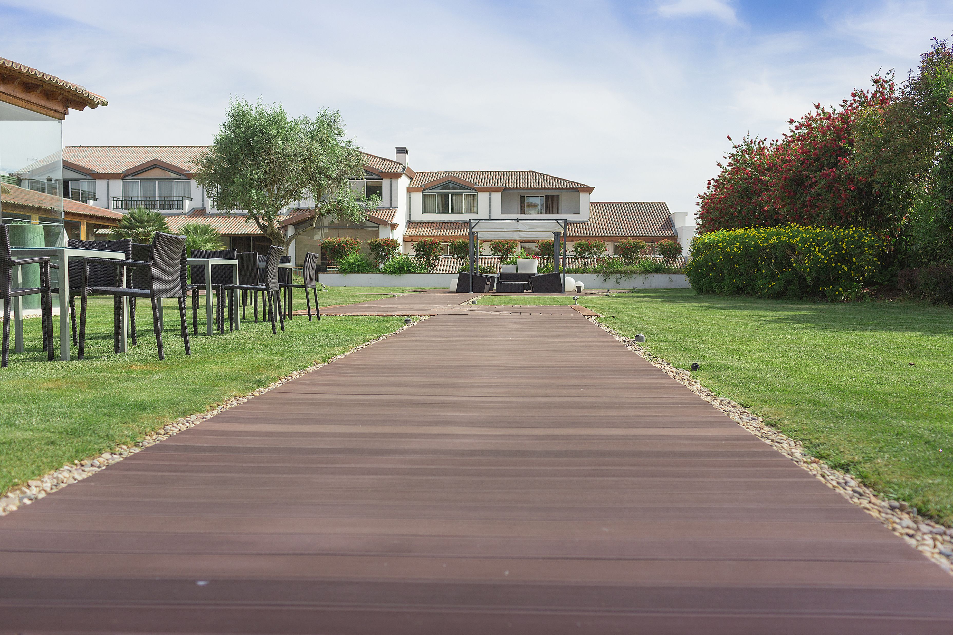A pathway leading to a building with outdoor seating and a well-maintained lawn.