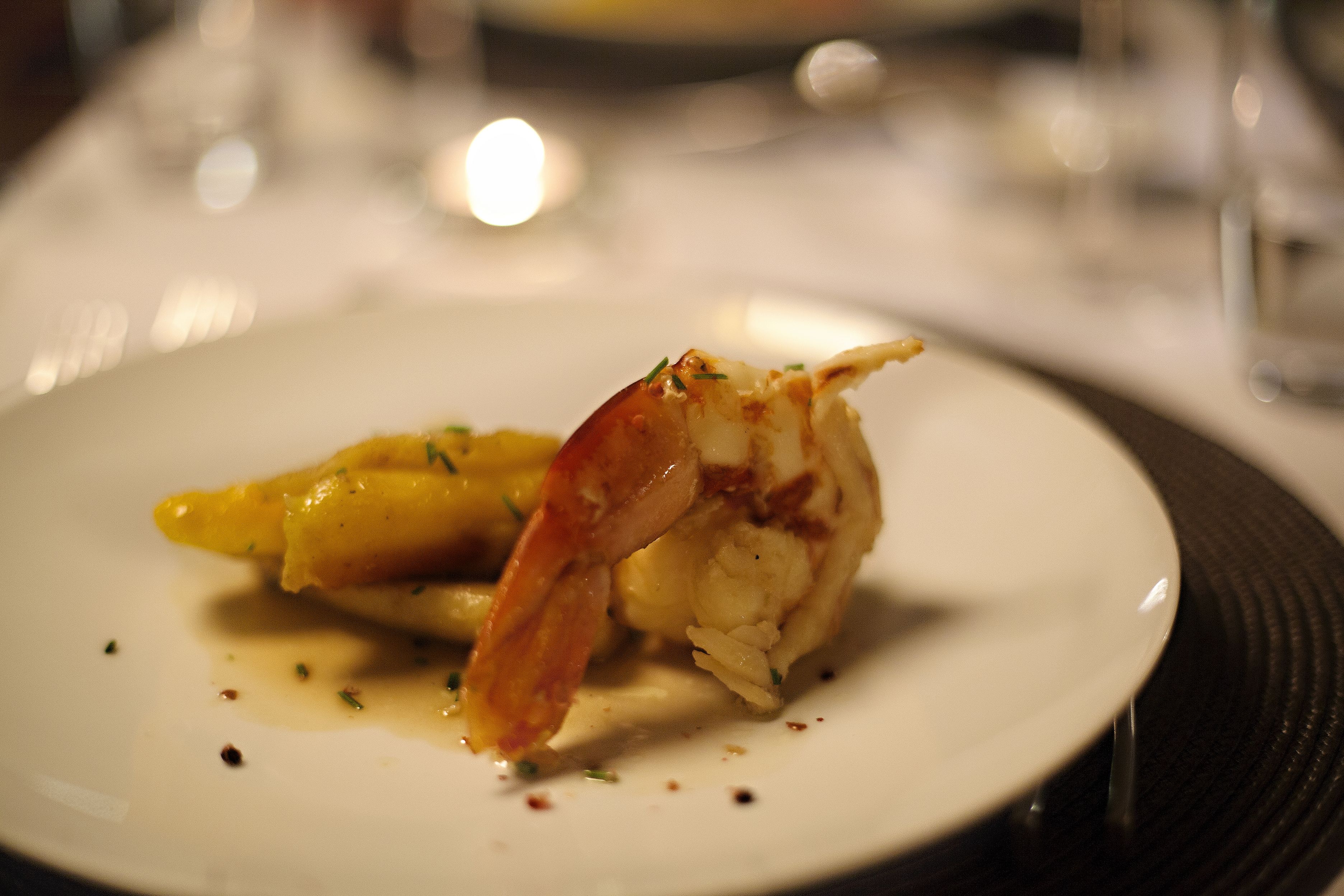 A plate with a seafood dish, possibly lobster, garnished with herbs.