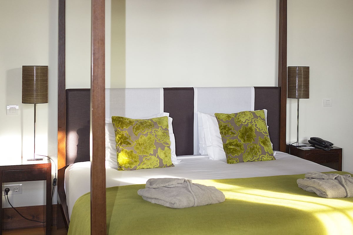 Un lit à baldaquin, une table de chevet avec une lampe et une petite table de nuit avec un téléphone.