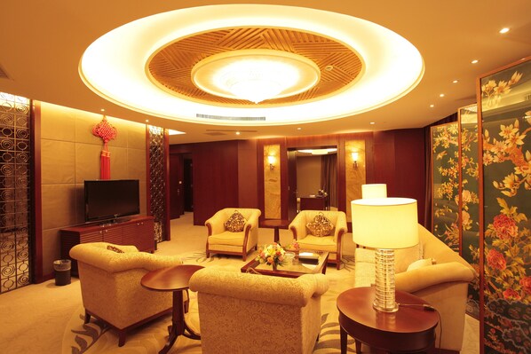 A hotel lobby with a television, sofas, a coffee table, and a decorative ceiling light.