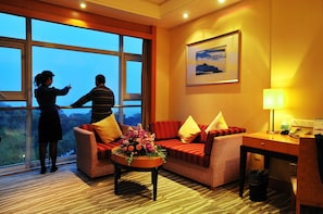 A hotel room with a large window, a sofa, a desk, and a lamp. - Dongshan Hotel (Suzhou)