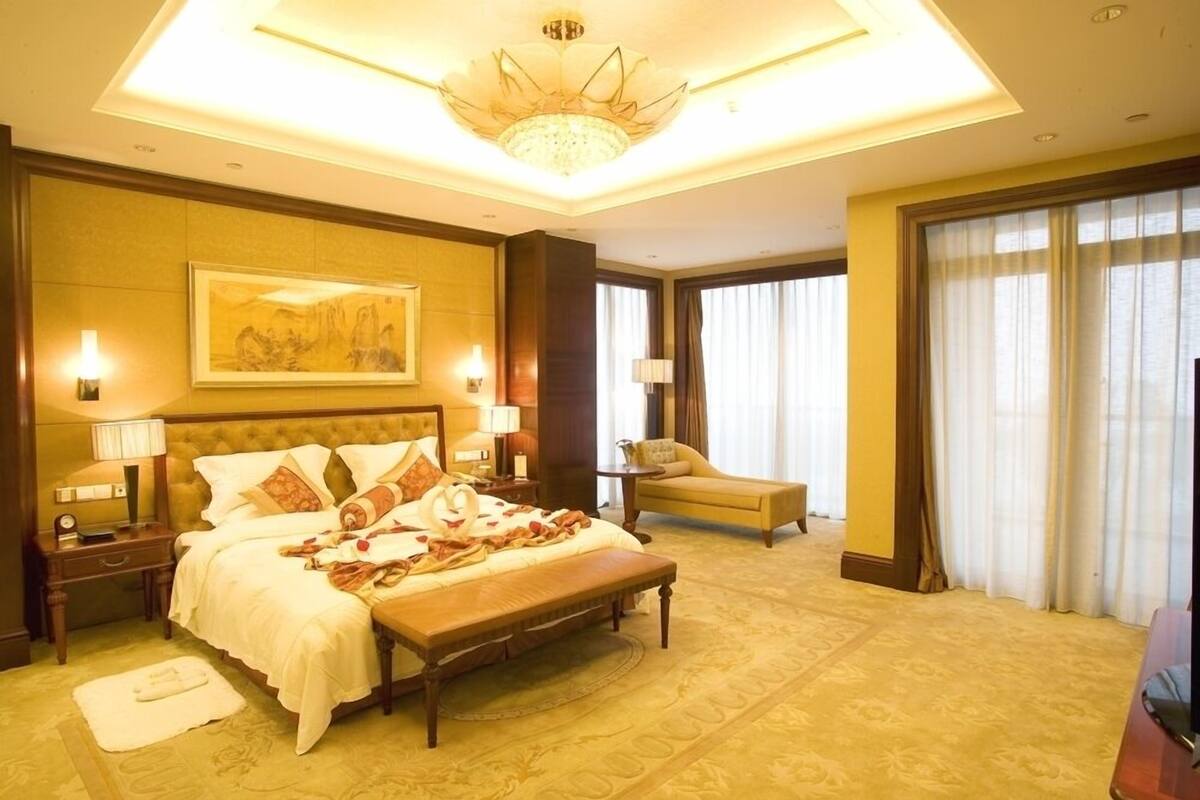 Amplia habitación de hotel con una cama grande, una zona de estar y vistas de la ciudad.