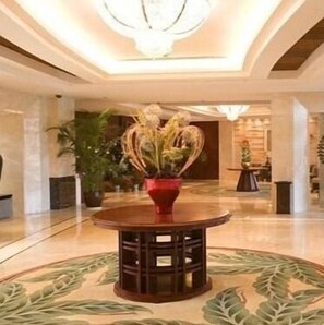 A lobby with a round wooden table, a potted plant, and a chandelier. - Dongshan Hotel (Suzhou)