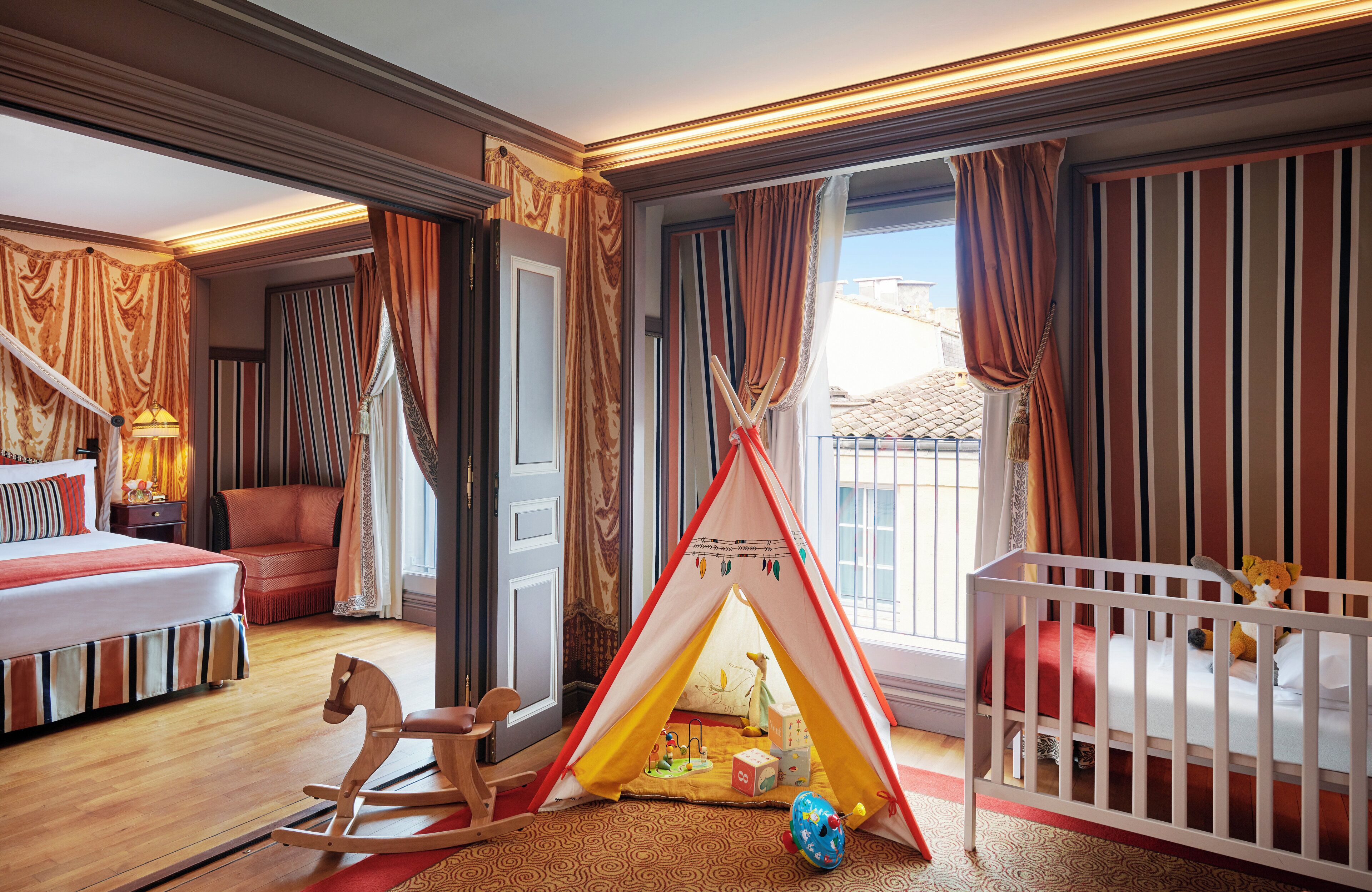 Una habitación infantil con una cuna, un caballo balancín y una tienda de juegos.