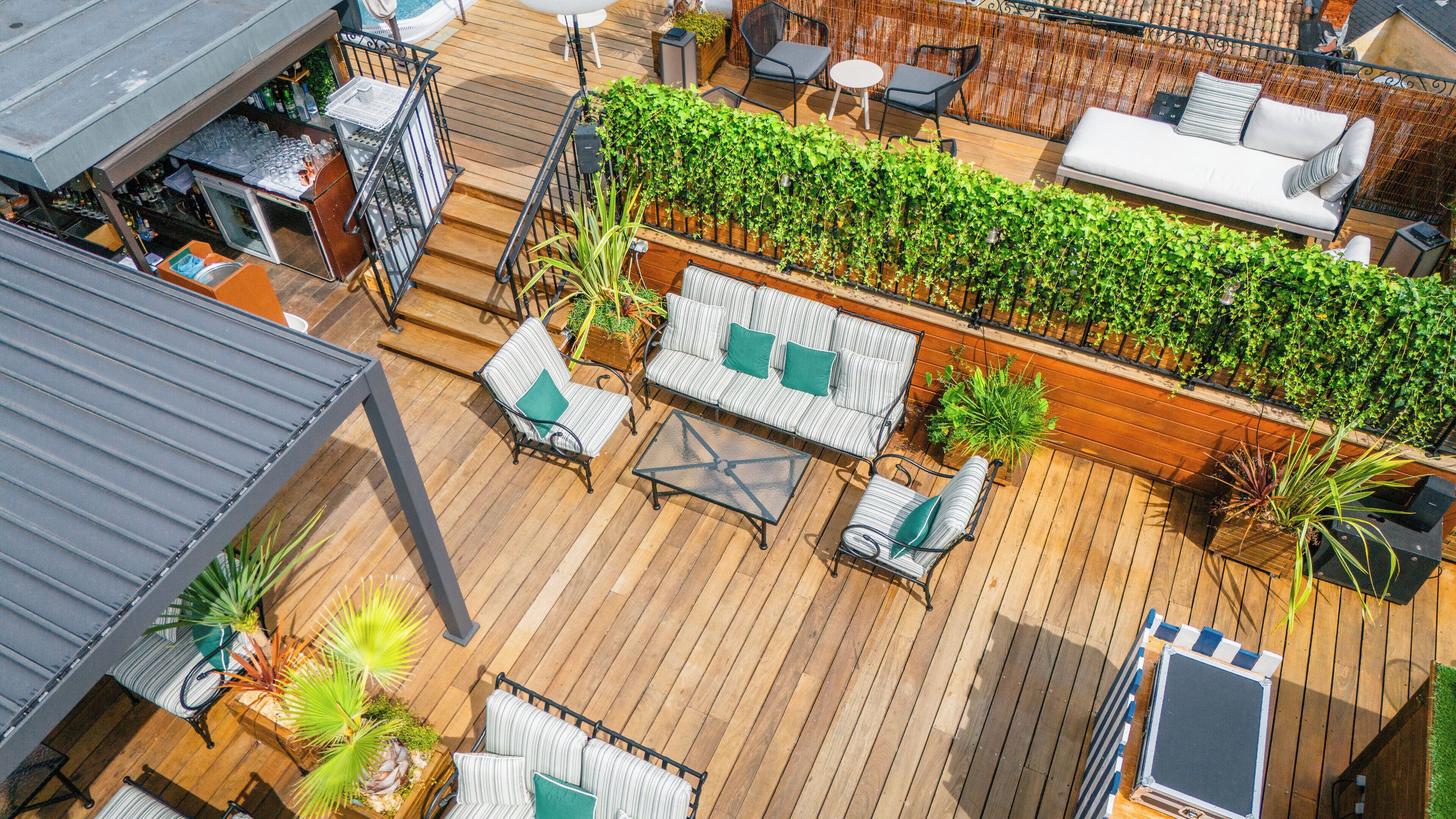 A wooden deck with outdoor seating, a white sofa, and a green plant wall.