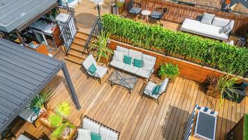 A wooden deck with outdoor seating, a white sofa, and a green plant wall.