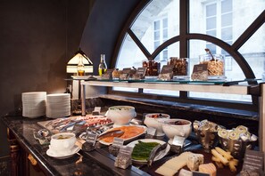 A buffet with various food items and condiments, arranged on a counter with a window view.