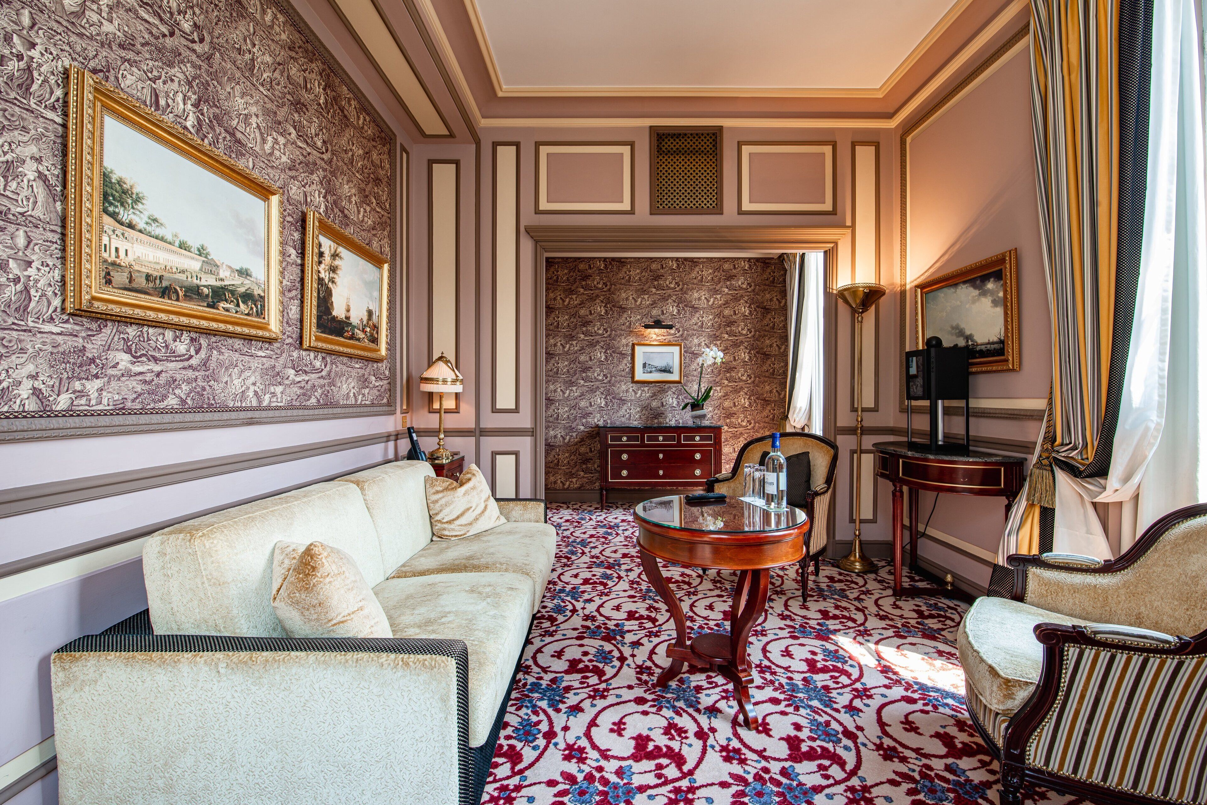 A room with a patterned wallpaper, a sofa, a coffee table, and a side table.