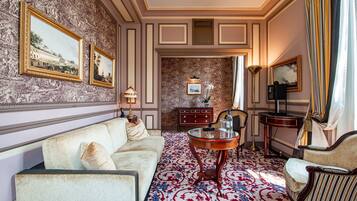 A room with a patterned wallpaper, a sofa, a coffee table, and a side table.