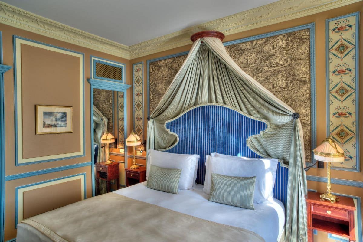 A bedroom with a canopy bed, decorative wall panels, and two bedside tables with lamps.