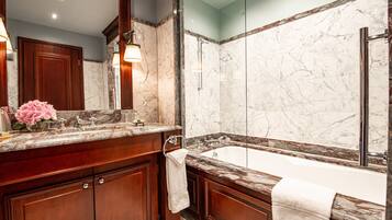 A luxurious bathroom with a marble sink, a large bathtub, and a glass-enclosed shower.