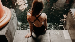 A person sitting on concrete steps by a body of water.