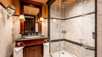 A modern bathroom with a glass-enclosed shower, a marble vanity, and dual sinks.