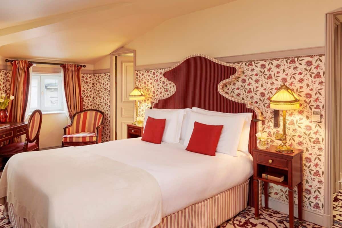 A hotel room with a large bed, two bedside tables with lamps, a chair, and a desk with a lamp.