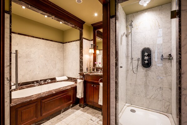 A luxurious bathroom with a large marble sink, a separate shower area, and a vanity with a mirror.