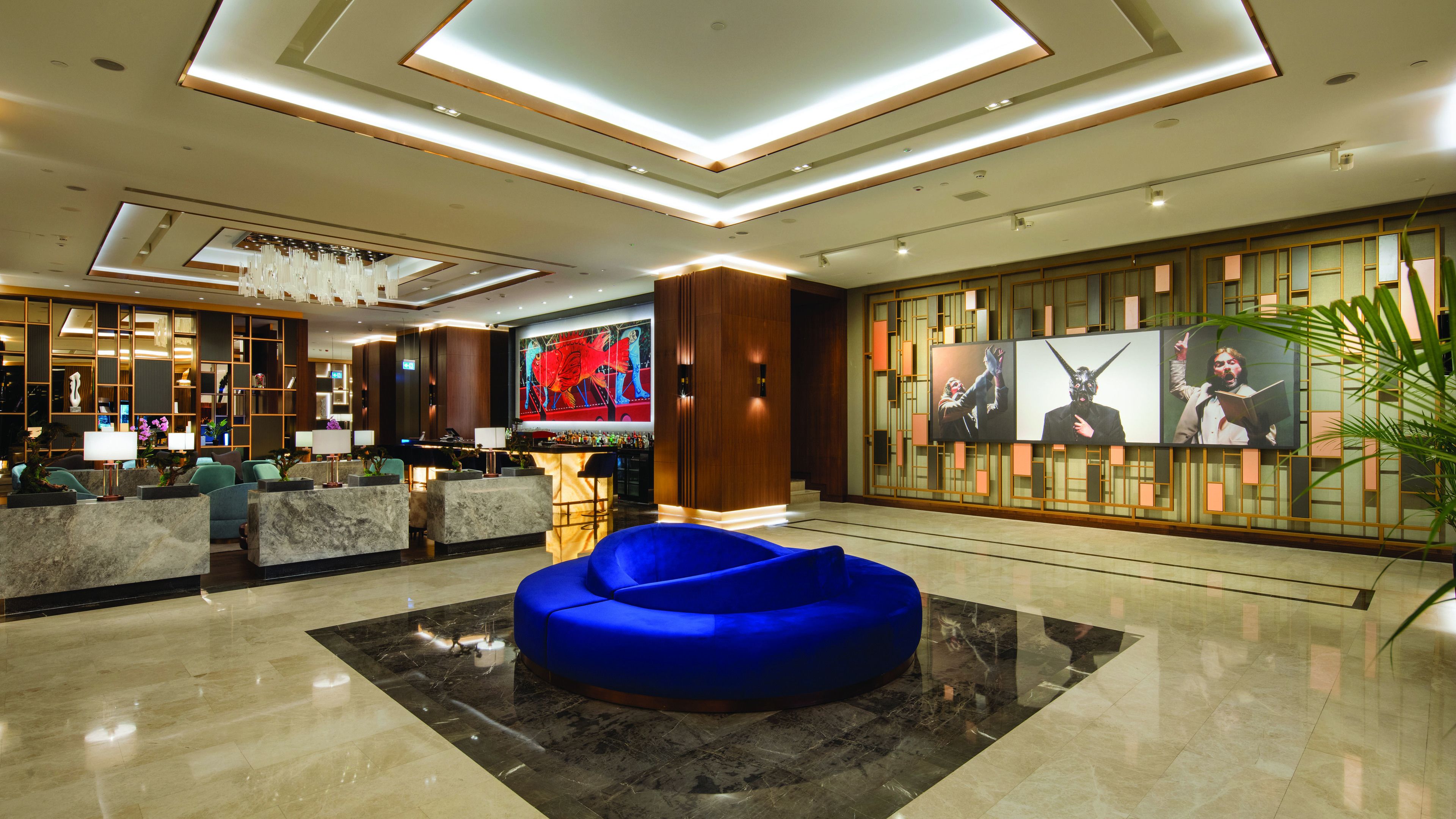 A modern lobby with a reception desk, seating area, and artwork on the walls.