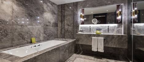Une salle de bain moderne avec une grande baignoire, un meuble-lavabo avec un miroir et un espace douche.